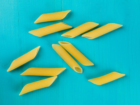 Italian Style Uncooked Penne Pasta Against a Blue Background
