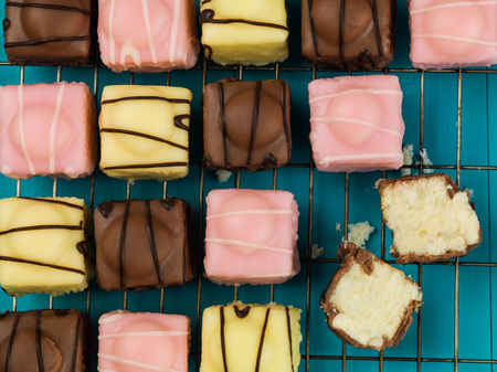 Iced Fondant Fancy Sponge Cakes Against a Blue Backgroundの写真素材