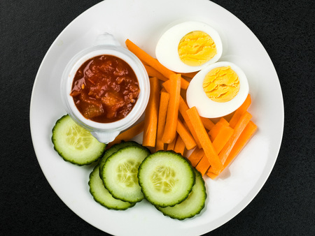 Egg Carrot and Cucumber Crudites With Tomato Salsa Against a Black Backgroundの写真素材
