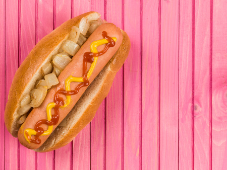 Hot Dog in a Bun With Fried Onion Ketchup and Mustard Against a Pink Backgroundの写真素材