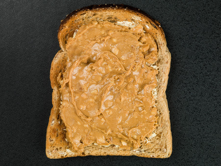 Crunchy Peanut Butter Spread on Toast Against a Black Background