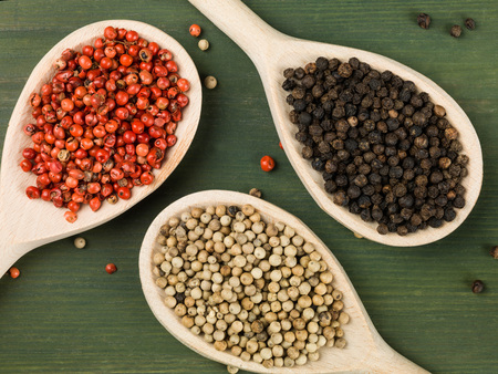 Whole Red White and Black Pepper Corns Against a Green Backgroundの写真素材