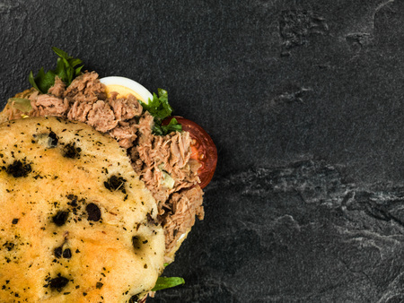 Tuna Nicoise Salad In a Focaccia Bread Bun Against a Black Slate Backgroundの写真素材