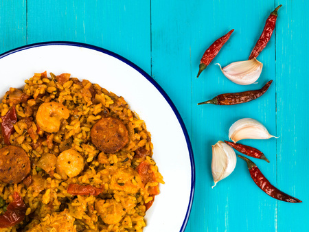 Chicken Smoked Chorizo and King Prawn Paella Meal Against a Blue Backgroundの写真素材