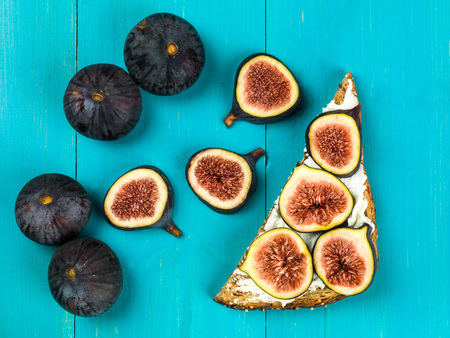 Fresh Figs and Cream Cheese on Wholegrain Toast Against a Blue Backgroundの写真素材
