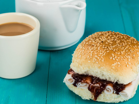 Sliced Turkey and Cranberry Sauce Bread Roll Against a Blue Backgroundの写真素材