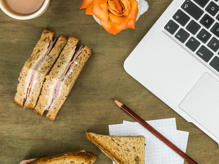 Ham and Cheese Sandwich in Brown Bread With a Cup of Tea At a Computer Workstationの写真素材