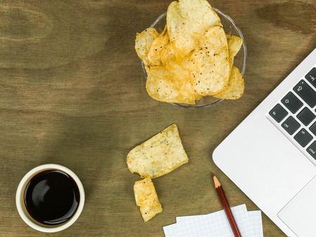 Computer Workstation With a Boewl of Potato Crisps or Potato Chips With a Cup of Black Coffeeの写真素材