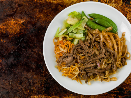 Thai Style Beef Noodles in Chilli Sauce Against a Distressed Oven or Baking Trayの写真素材