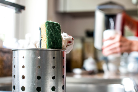 Kitchen Utensil Tidy Container With A Scouring Pad and Pouring Tea Or Coffee In The Background