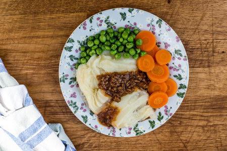 Cottage Pie With Peas and Carrots and Gravy Against a Dark Textured Backgroundの写真素材