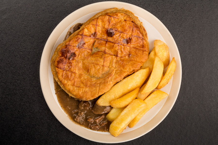 Beef Steak Pie With A Puff Pastry Crust Top And Chips On A Black Backgroundの写真素材