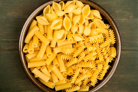 Selection of Dried Uncooked Italian Style Pasta Conchiglioni Rigatoni and Fusilli On A Green Wooden Backgroundの写真素材