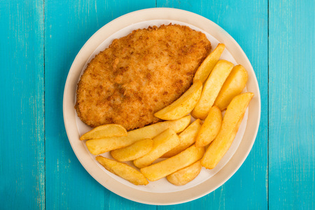 Breaded Chicken Fillet With Chunky Chips On A Blue Wooden Backgroundの写真素材