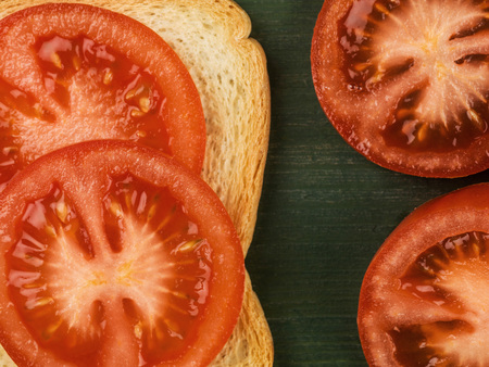Sliced Tomato on French Toast Against a Green Backgroundの写真素材