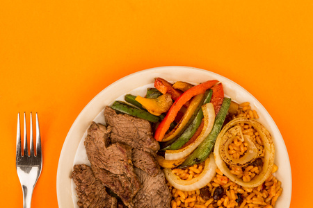 Mexican Style Steak Fajitas With Spicy Rice and Peppers Against An Orange Backgroundの写真素材