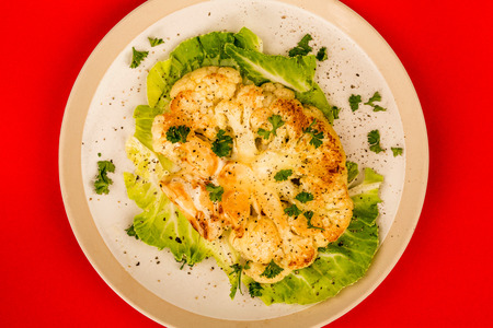 Cooked Cauliflower Steak Vegetarian or Vegan Meal Against A Red Backgroundの写真素材
