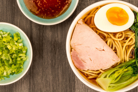  Bowl Of Japanese Style Pork Ramen Noodle Soup With Pak Choi And A Boiled Egg Against A dark Wooden Table Topの写真素材
