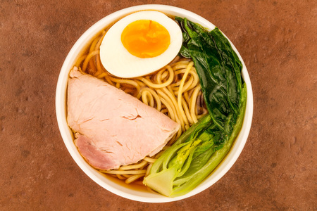  Bowl Of Japanese Style Pork Ramen Noodle Soup With Pak Choi And A Boiled Egg Against A Red Tiled Backgroundの写真素材
