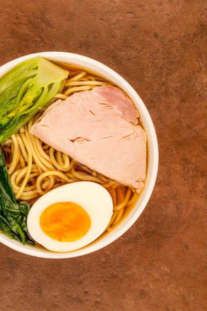  Bowl Of Japanese Style Pork Ramen Noodle Soup With Pak Choi And A Boiled Egg Against A Red Tiled Backgroundの写真素材