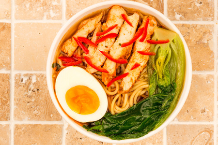 Japanese Style Chicken And Chilli Ramen Soup or Broth With Pak Choi On A Tiled Kitchen Table Topの写真素材