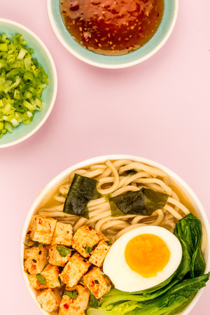 Japanese Style Vegetarian Tofu Noodle Ramen Soup or Broth Against A Pale Pink Backgroundの写真素材