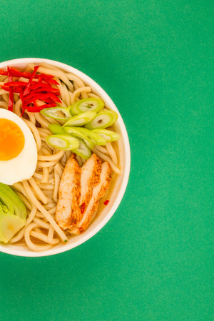 Japanese Style Chicken and Udon Noodle Broth or Soup With Pak Choi And Red Chillies Against A Green Backgroundの写真素材