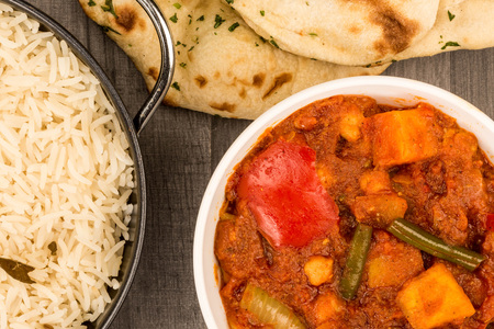 Indian Style Vegetarian Masala Curry Against A Dark Wooden Table Top With Basmati Rice And Naan Breadの写真素材