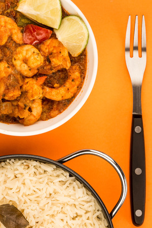 Spicy Indian Style King Prawn Bhuna Curry Against An Orange Background With Basmati Riceの写真素材