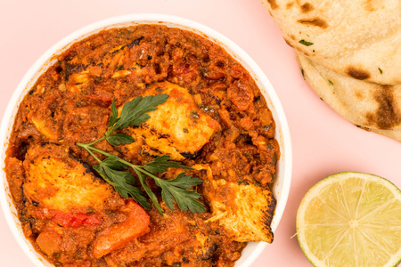 Indian Style Chicken Balti Curry Against A Pink Background With Naan Bread And Fresh Limeの写真素材