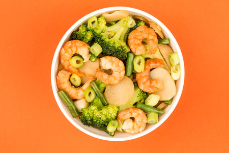 Chinese Style King Prawn With Ginger Broccoli And Spring Onions Against A Red Backgroundの写真素材