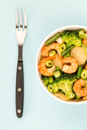 Chinese Style King Prawn With Ginger Broccoli And Spring Onions Against A Blue Backgroundの写真素材