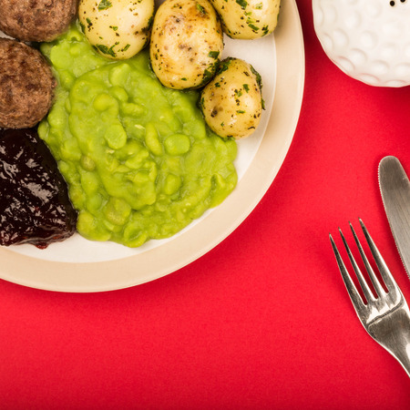 Swedish Style Meatballs With Boiled Potatoes And Mushy Peas Against A Red Background With Copy Spaceの写真素材