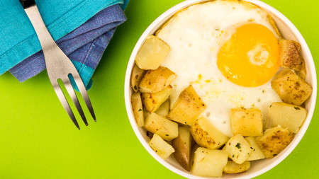 Fried Egg With Fried Potatoes Breakfast In A Bowl Against A Green Backgroundの写真素材