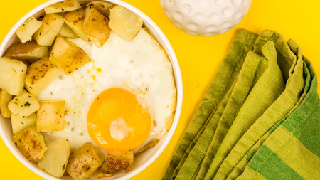 Fried Egg With Fried Potatoes Breakfast In A Bowl Against A Yellow Backgroundの写真素材