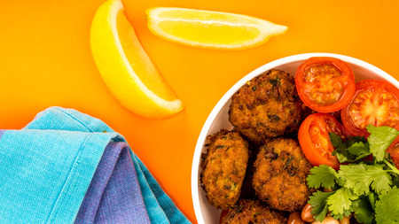 Bowl Of Vegetarian Or Vegan Falafel Beans Coriander And Tomatoes Buddha Bowl Against An Orange Backgroundの写真素材