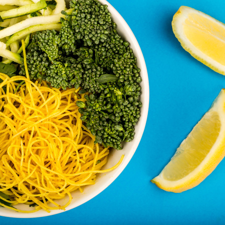 Healthy Vegetarian Or Vegan Noodle Buddha Bowl With Courgettes Broccoli And Coriander Against A Blue Backgroundの写真素材