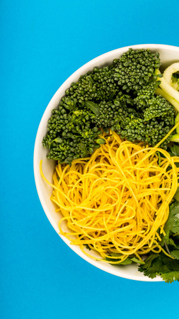 Healthy Vegetarian Or Vegan Noodle Buddha Bowl With Courgettes Broccoli And Coriander Against A Blue...