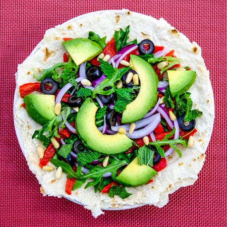 Healthy Vegetarian Avocado Salad on a Pizza Base With Red Onions, Red Peppers Mint and Black Olivesの写真素材