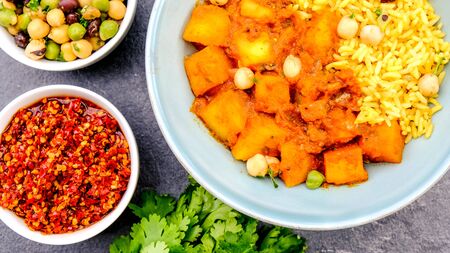 Indian Style Spicy Traditional Potato Vegetarian Curry With Yellow Pilau Rice and Chickpeasの写真素材