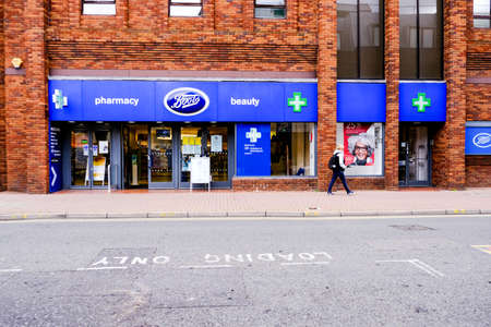 Empty COVID-19 High Street Boots Pharmacy Or Chemist Single Person Walking Byのeditorial素材