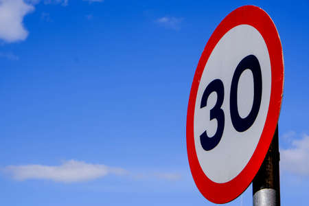 Road Traffic 30mph Speed Limit Sign, Against A blue Summer Skyの写真素材