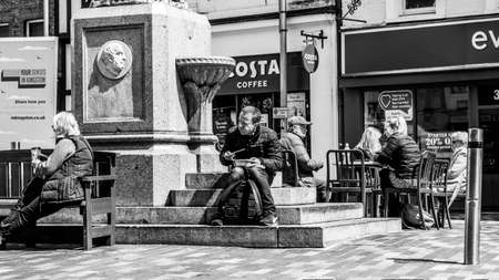 Kingston Upon Thames London UK, May 04 2021, Black and White Image Man Sitting On Steps Eating...