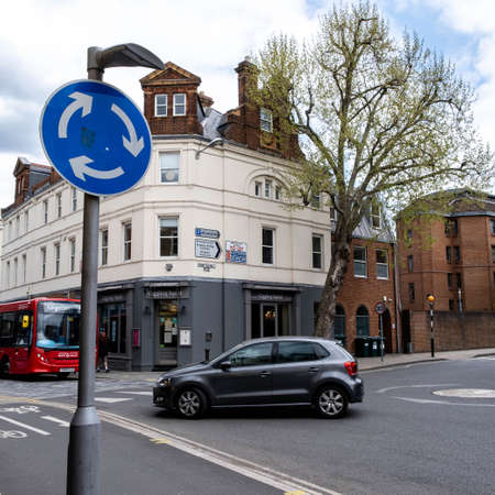 Kingston Upon Thames London UK, May 07 2021, A Car And Bus Approaching A Roundabout With A Blue Traffic Road Signのeditorial素材