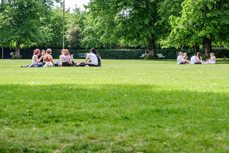 Epsom Surrey, London, May 09 2022, Groups Of Young People Sitting On The Grass In A Park Relaxing...