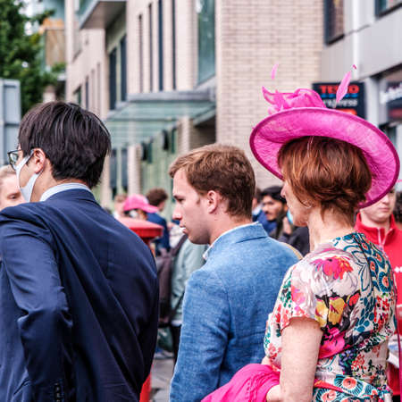 Epsom Surrey, London UK, June 04 2022, Woman Wearing Floral Print Dress And Pink Hat With Two Menのeditorial素材