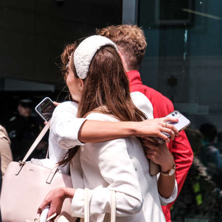 Epsom Surrey, London UK, June 04 2022, Two Affectionate Young Women Meeting  Hugging And Embacing Holding Mobile Phonesのeditorial素材