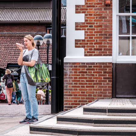 Epsom Surrey, London UK, June 10 2022, Attractive Young Woman Carrying Shopping Bag Using Mobile Phoneのeditorial素材