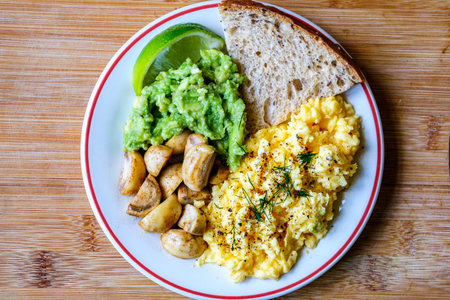 London UK June 25 2025,  Scambled Eggs With Mashed Avacado Fried Musherooms and Seeded Breadの写真素材