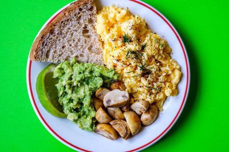 London UK June 25 2025,  Scambled Eggs With Mashed Avacado Fried Musherooms and Seeded Breadの写真素材